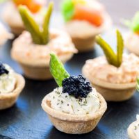 Multiple mini puff pastry tartlets with savory filling.